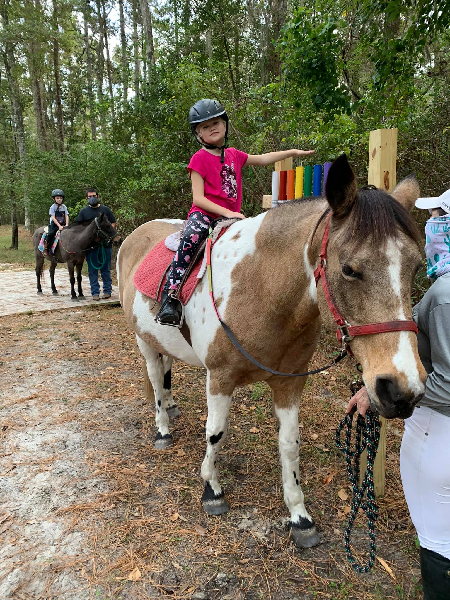 A child sits on a pony that is held by a nearby adult